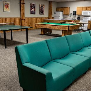 Lounge area of Scott Residence Hall with a couch, ping pong table and pool table.