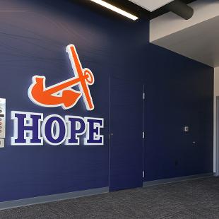 The Hope logo with the orange anchor and blue HOPE letters in the navy entry way of the  Jim Herringa Athletic Center.