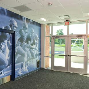 The wall outside the athletic training / rehabilitation room is a huge photography from a football game.