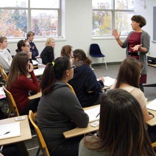 Students engage with a professor in a classroom of Van Zoeren Hall